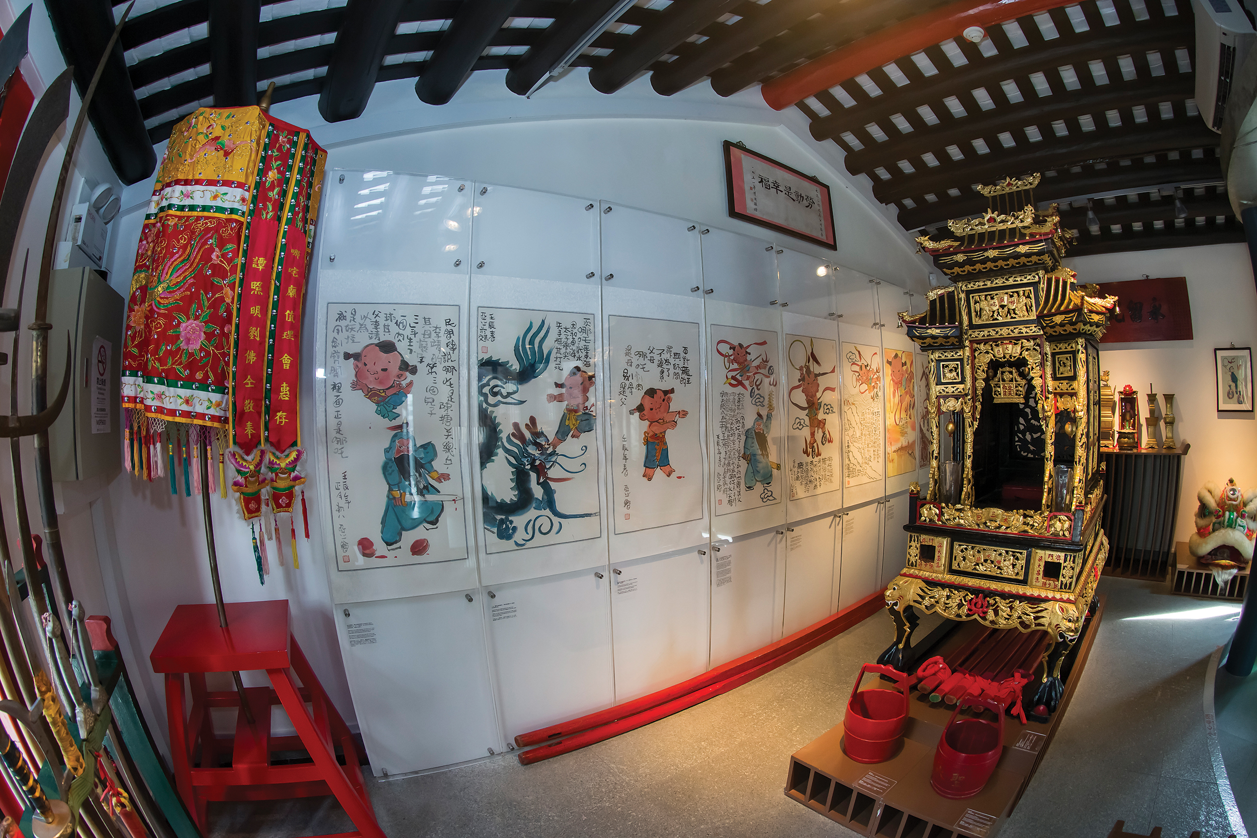 The iconic sedan chair in front of illustrations of Na Tcha by cartoonist Ah-Cheng inside the Na Tcha Exhibition Room - Photo by Eric Tam