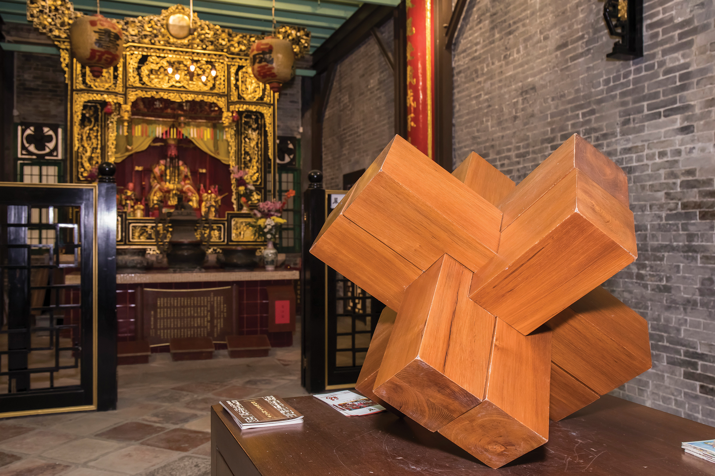 A large wooden Lu Ban lock is displayed in front of an altar, right next to the entrance to the Exhibition Room of Master Lu Ban’s Woodcraft Works - Photo by António Sanmarful