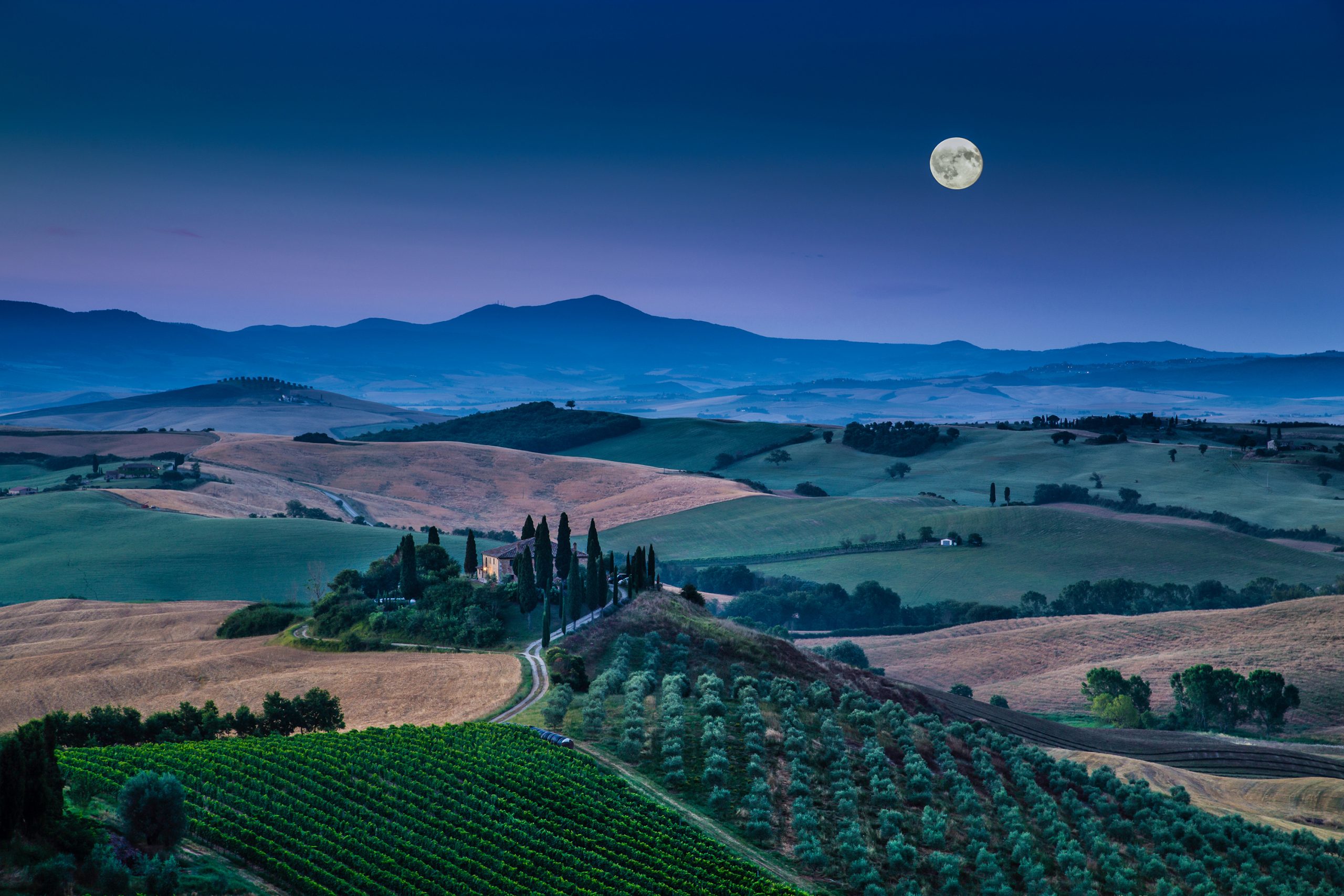 Panoramic view of scenic Tuscany landscape with rolling hills and valleys in beautiful moonlight at dawn, Val d'Orcia, Italy