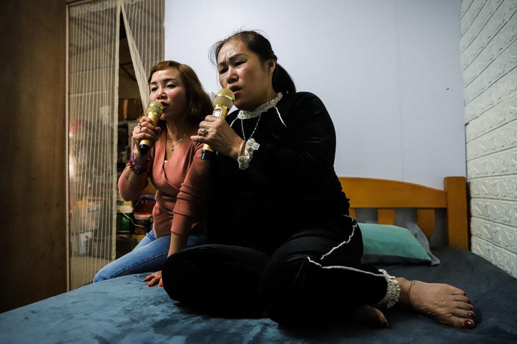 Nguyen Hai, 48,(right) and Bui Huong Lieu , 57, sing karaoke at the house that they share with several other Vietnamese women in Macao, on 19 November 2023
