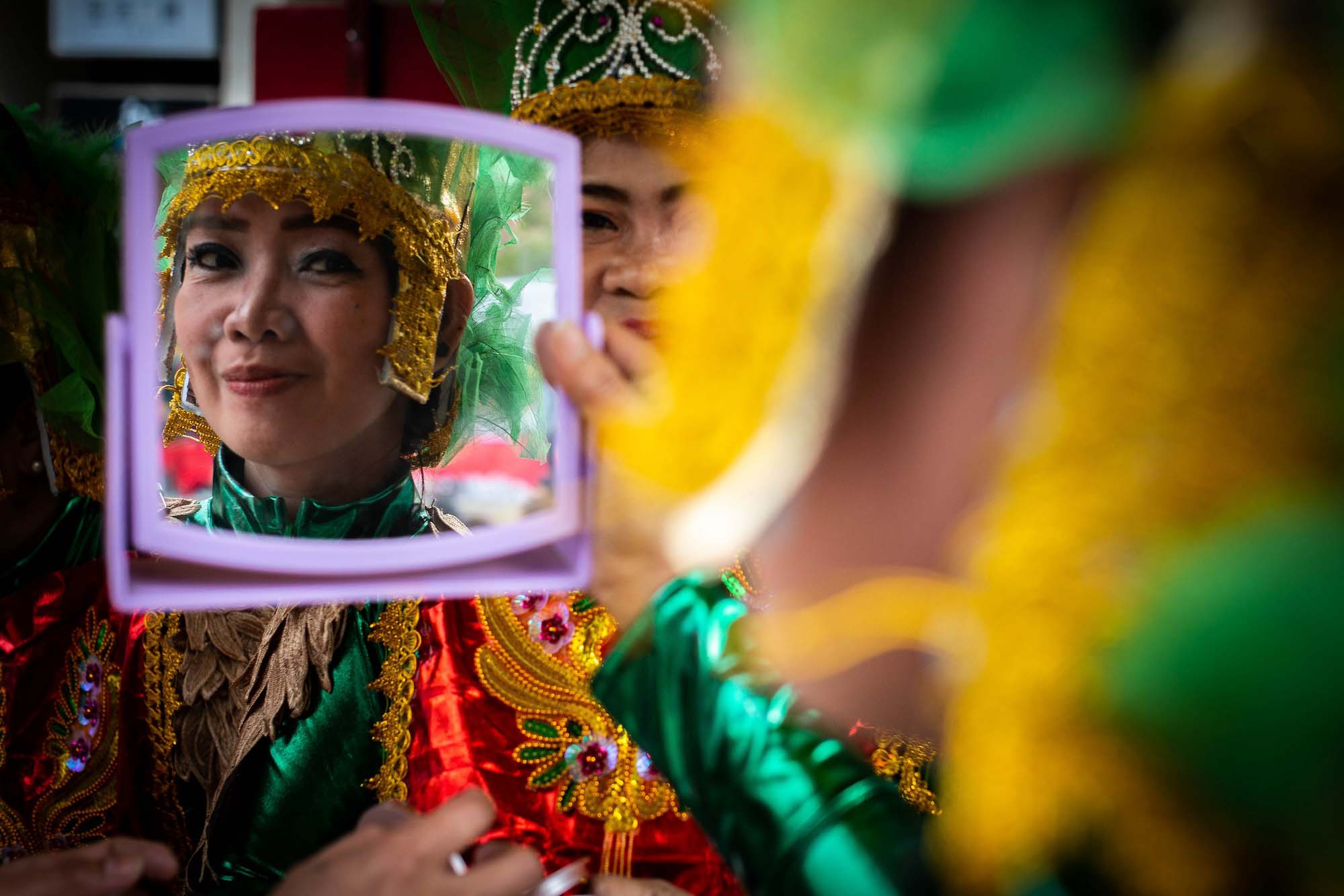 A member of the National Philippine Guardians Incorporated dance troupe checks herself in a mirror before performing at Sinulog