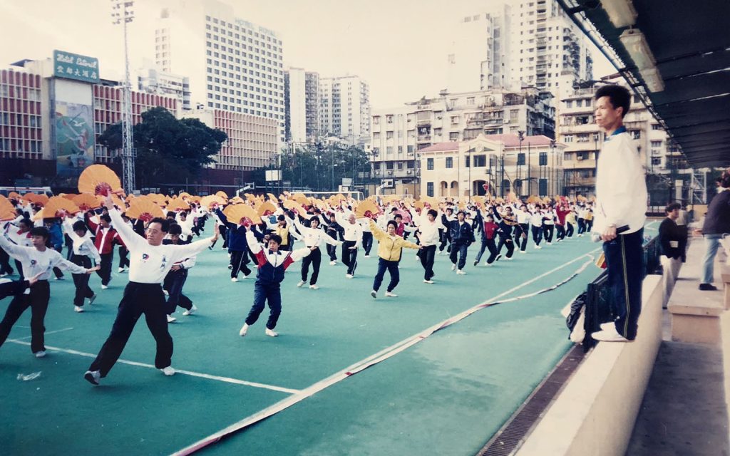 Leong Chong Leng, seen here standing on the low wall to the right of the picture, leads 1,200 tai chi performers at the former Tap Seac football grounds in rehearsals for the Macao handover performance in 1999