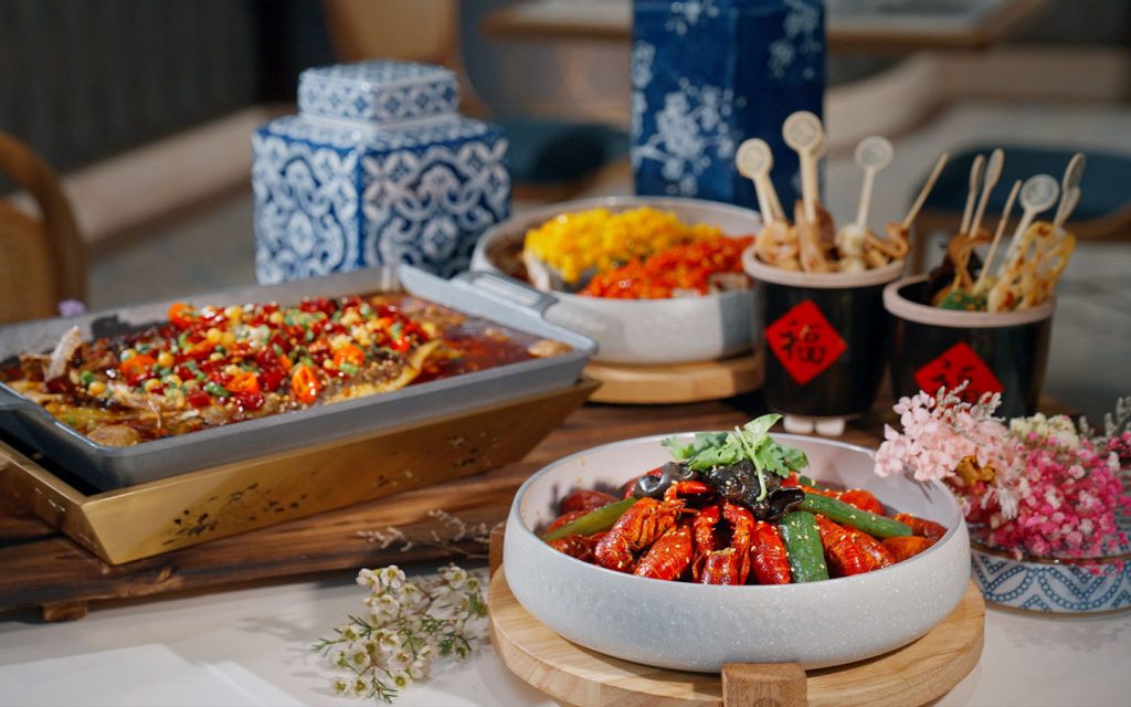 Experience the addictive numbing heat of Sichuan classics like spicy crawfish (front centre) alongside Chongqing favourites such as grilled fish (left) in green pepper and chilli broth