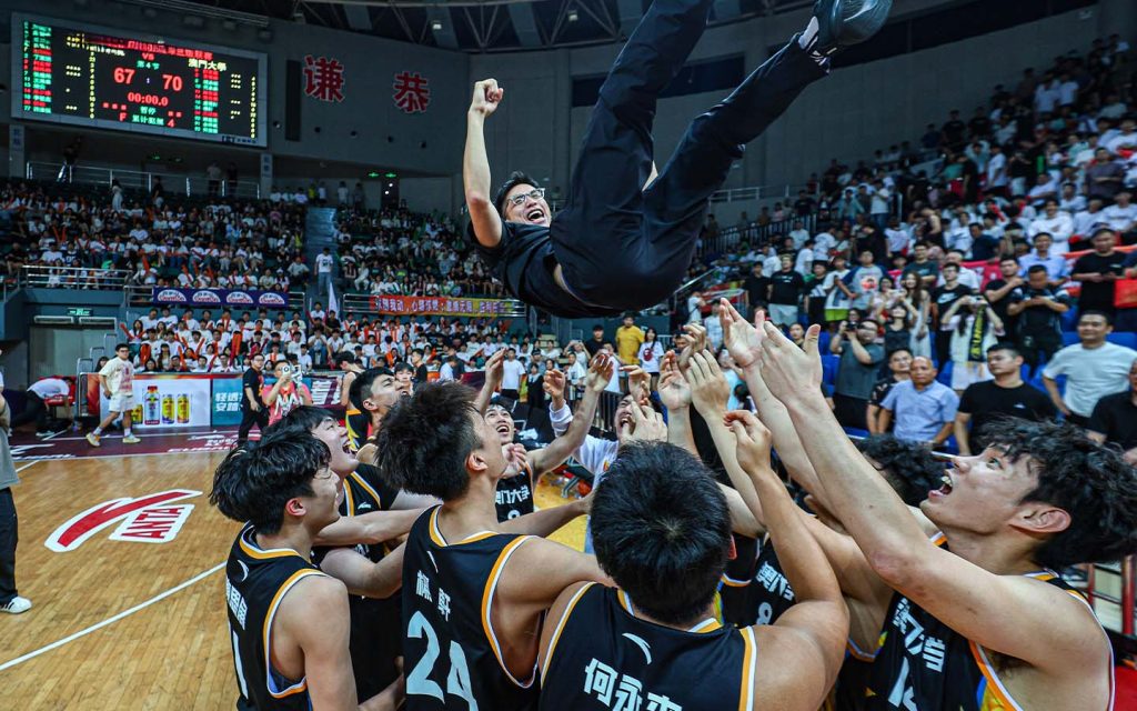 Players lift Coach Lam into the air after celebrating their shared victory