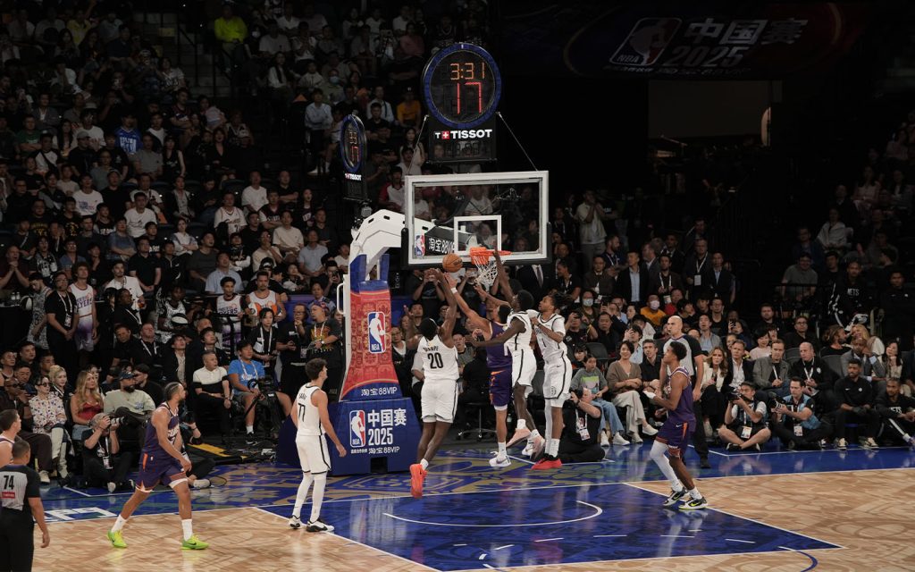 Phoenix Suns’ Devin Booker tries a layup between three Brooklyn Nets defenders