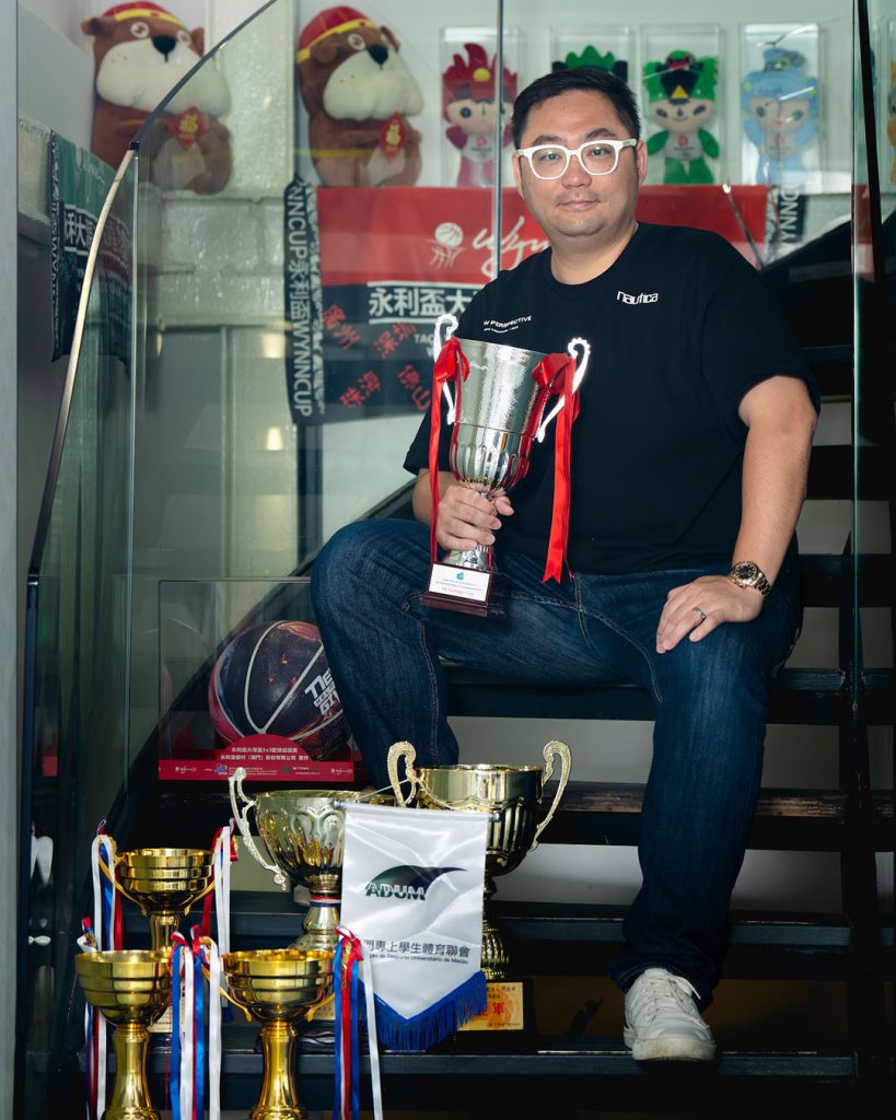 Ryo Lou poses with trophies and memorabilia celebrating years of involvement in Macao’s sports scene